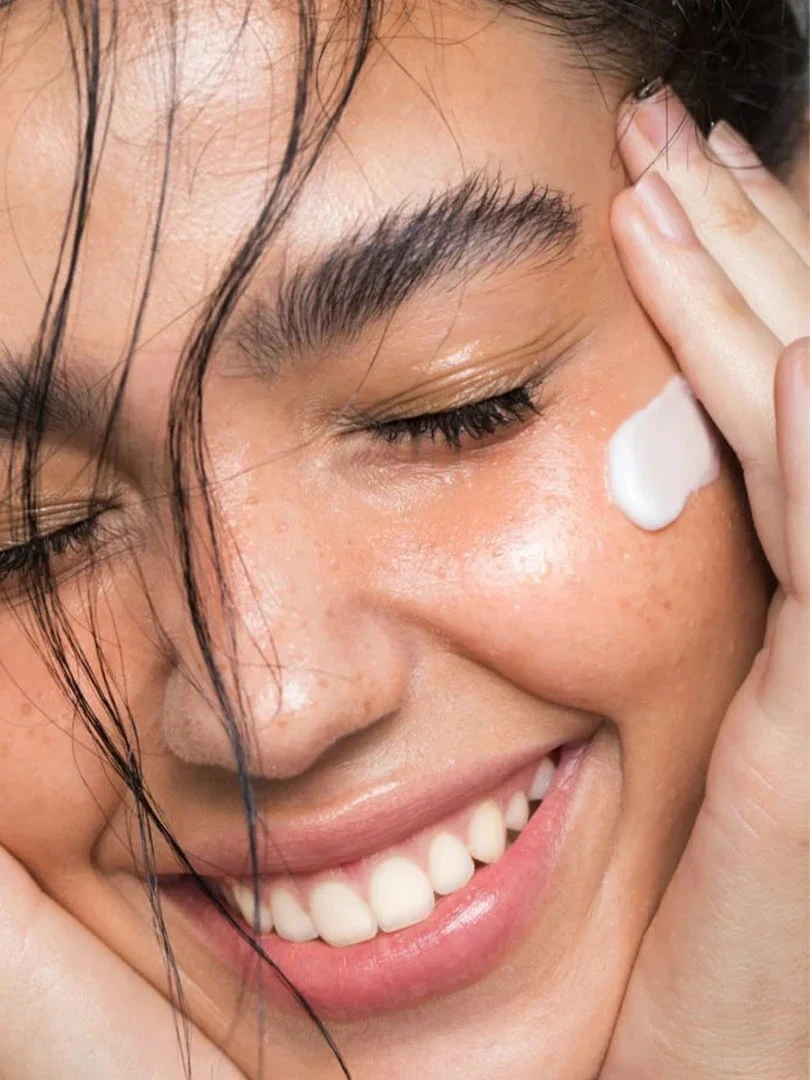 Smiling woman with cream on her cheek